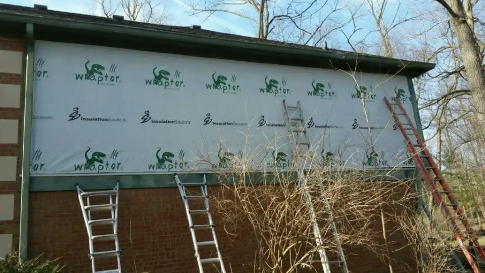 Guy Painting carpenters mid-project with Wrapter house wrap installed over new sheathing