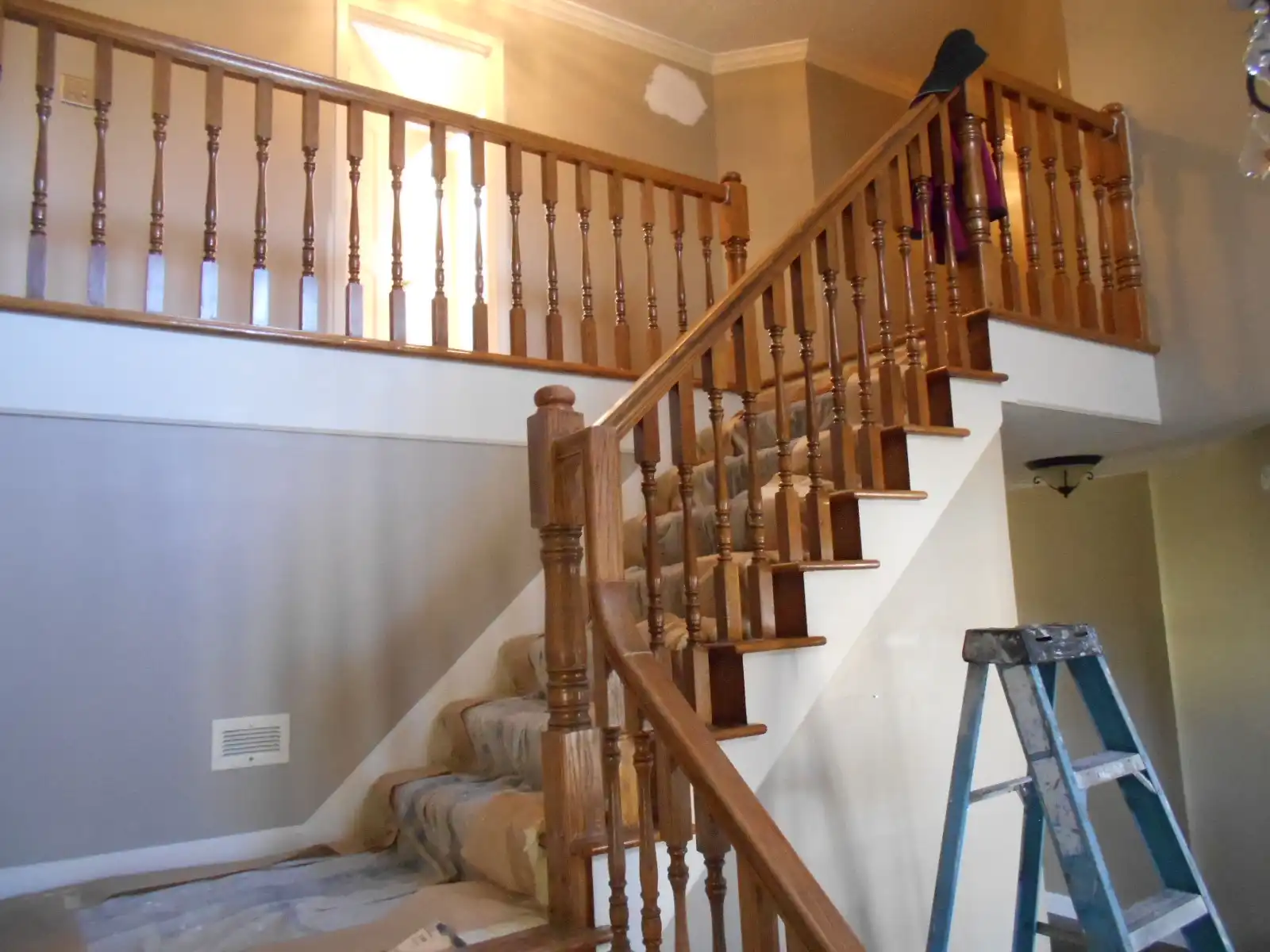 Curved staircase with stained honey-oak balusters and handrail, before painting