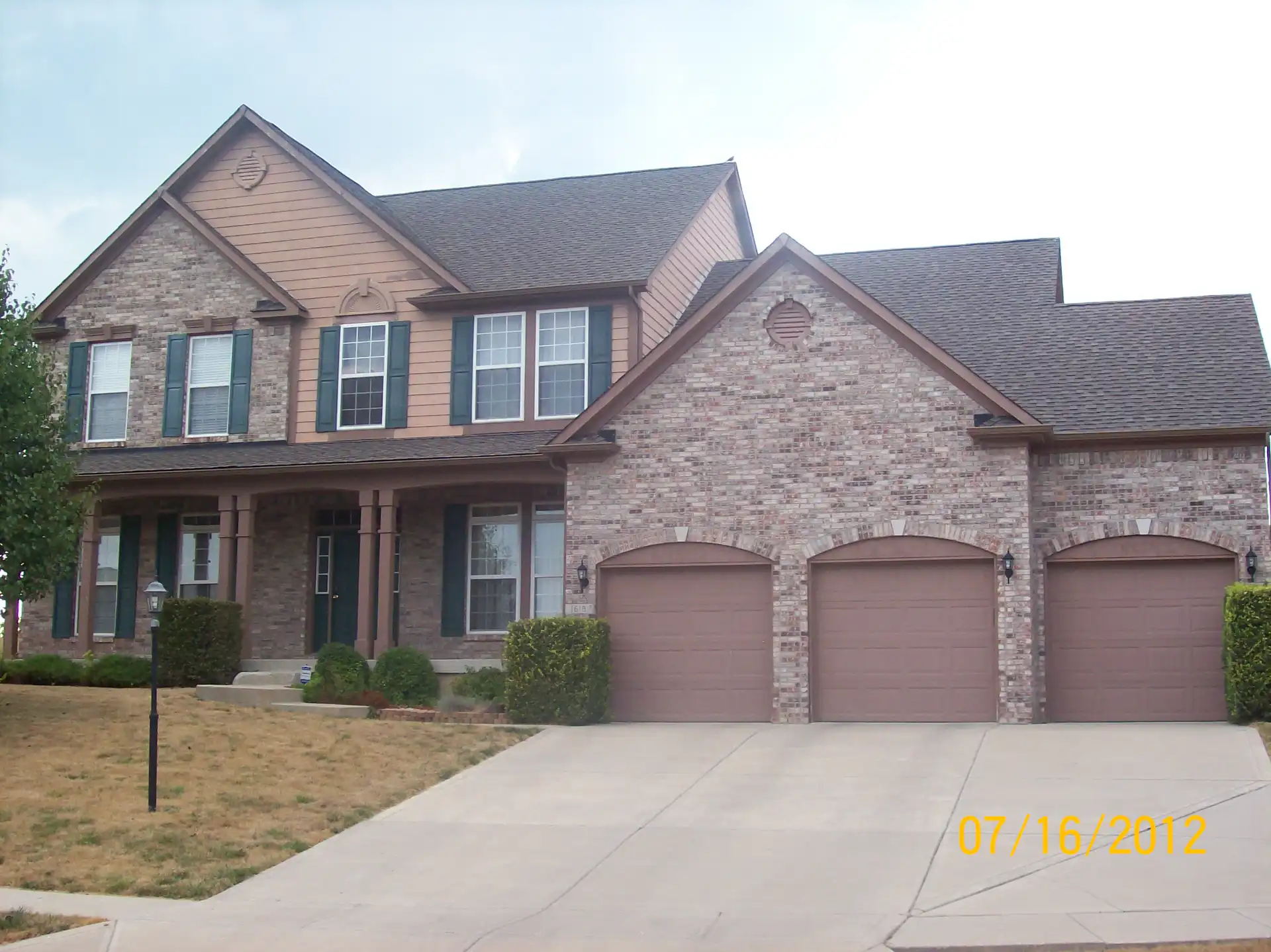 Central Indiana home exterior with tan siding and teal shutters, before repaint
